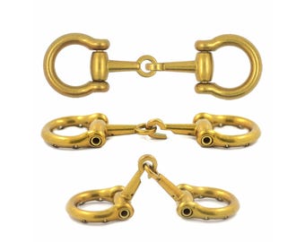 May include: A set of three brass-toned metal horse bit connectors shown from different angles. Each piece features two circular loops connected by a central hinge mechanism, with a matte finish and small circular rivets along the outer edges.