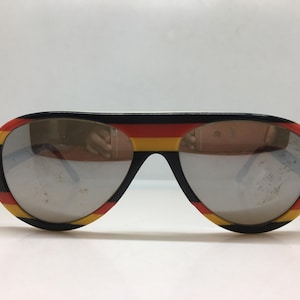 May include: A white ceramic mug with a black handle and the text "But First, Coffee" in a black, bold font. The mug is on a white surface. The mug is approximately 10 cm tall.