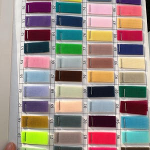 May include: A color swatch chart featuring forty-eight rectangular fabric samples of tulle mesh, each attached with a metal staple. The samples are arranged in a grid, numbered 49 through 96, displaying a wide variety of vibrant and pastel colors.