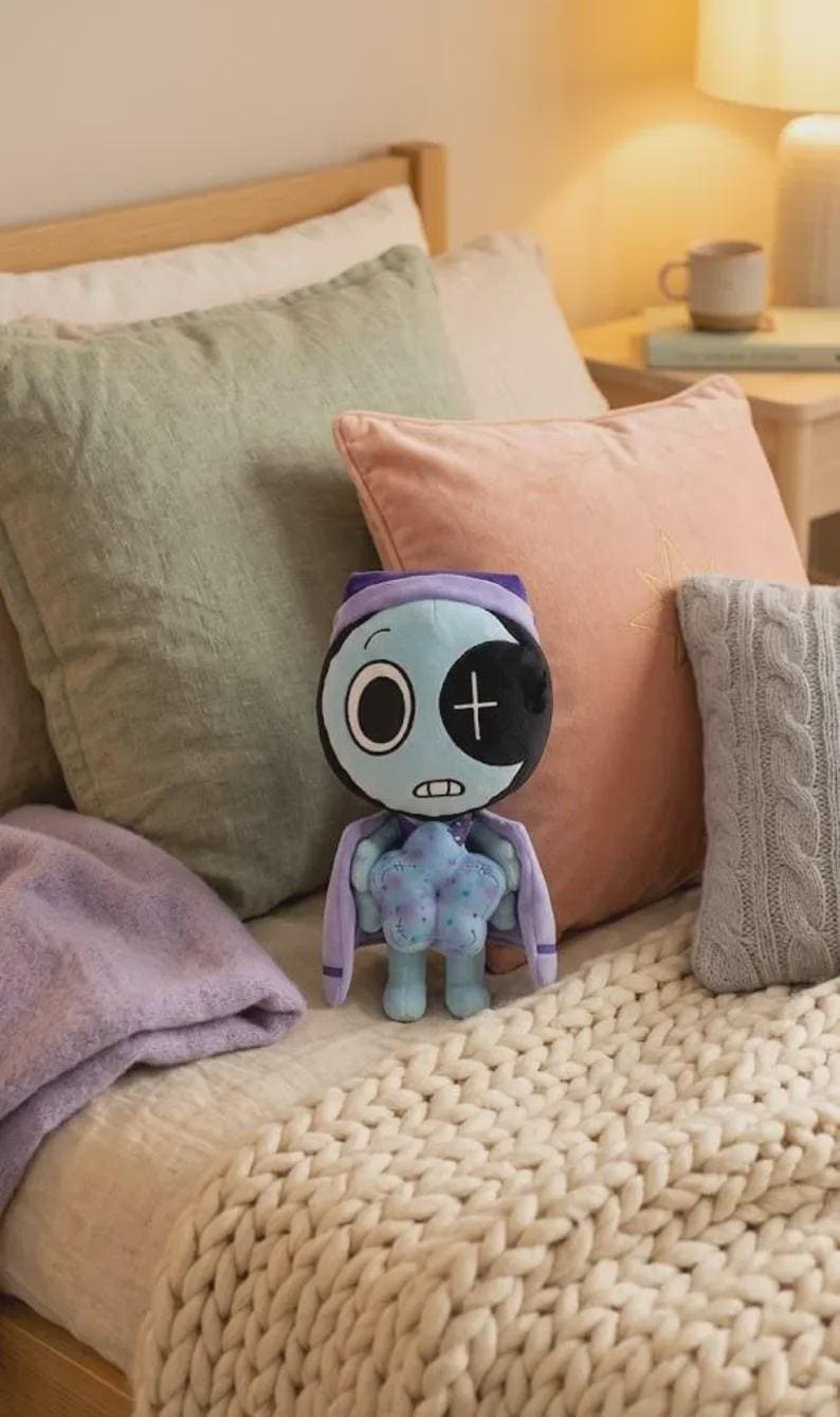 May include: A plush toy featuring a light blue, round head with a large white eye on the left and a black eye patch with a white cross on the right. It has a small mouth, a purple hood, and a light blue body holding a star-shaped object.