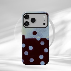 May include: A smartphone case with a unique design. The top section has a light blue and white spray paint effect, while the bottom is a deep burgundy with light blue polka dots. The case has a glossy finish and a camera cutout.
