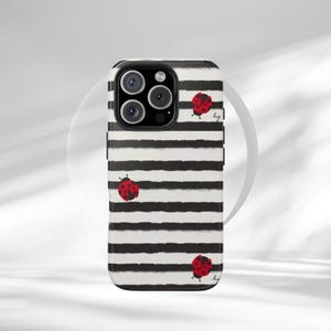 May include: A white and black striped phone case with three red ladybug illustrations. The case has a glossy finish and a camera cutout. The ladybugs have black spots and are scattered across the case.
