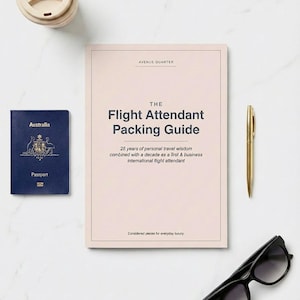 Könnte beinhalten: Eine Draufsicht mit Reiseutensilien. Ein Reisepass, ein Buch mit dem Titel "The Flight Attendant Packing Guide", ein goldener Stift, eine schwarze Sonnenbrille und ein Reisebecher sind auf einer weißen Marmoroberfläche angeordnet.