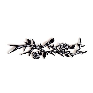 May include: Black and white embroidered patch featuring a rose branch with thorns and two roses. The patch is a detailed, stylized design, perfect for adding to clothing or accessories. The patch is set against a white background.
