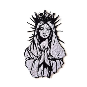 Può includere: Toppa ricamata in bianco e nero raffigurante una figura incoronata con le mani giunte in preghiera. Il disegno include un'aureola e tratti del viso dettagliati, adatta per abbigliamento o accessori.