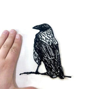 May include: A white ceramic mug with a black handle and the text "But First, Coffee" in a handwritten style. The mug is on a white surface. The mug is approximately 4 inches tall.