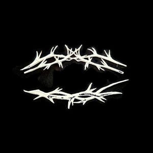 May include: Two white, thorn-like objects are arranged in a horizontal, eye-like shape against a black background. The objects have a rough texture and sharp points, resembling a crown of thorns. The image is a minimalist, symbolic representation.