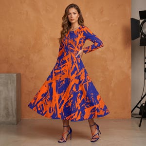 May include: A long-sleeved dress with a vibrant orange and blue abstract pattern. The dress has a flowing skirt and is paired with blue strappy heels. The model is standing in front of a brown background.
