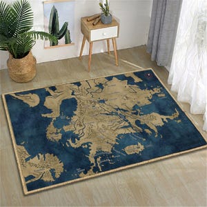 May include: A rectangular rug featuring a map design in blue and tan hues. The rug displays a detailed geographical layout with text labels and a rope-style border. It's placed on a wooden floor, with a plant and a side table visible in the background.