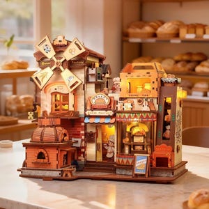 Op de afbeelding: Een gedetailleerd houten model van een bakkerij met een draaiende windmolen, een stenen oven en binnenverlichting. De structuur bevat borden met de tekst Bakery, Bread Factory en Classic, met miniatuurfiguren van bakkers en brooddisplays.