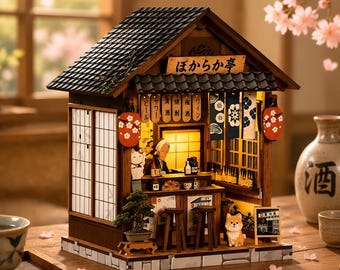 May include: A miniature wooden Japanese izakaya model featuring a dark tiled roof, a sign with the text ぼからか亭, hanging lanterns, a bonsai tree, a small dog figurine, and an interior counter with bottles and a person figure illuminated by warm light.