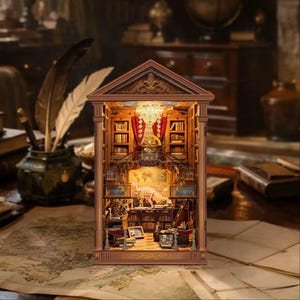May include: A miniature wooden library book nook insert featuring a detailed interior with illuminated bookshelves, a central crystal chandelier, red curtains, a dinosaur skeleton display, and a sign that reads LIBRARY in gold lettering.