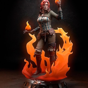 Peut inclure: Figurine détaillée d'une femme aux cheveux roux, vêtue d'un haut rayé vert et blanc, d'un pantalon marron et de bottes. Elle tient deux flammes orange incandescentes. La figurine repose sur une base entourée de flammes orange stylisées.