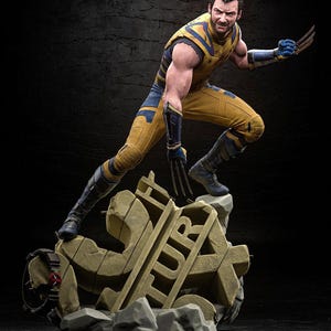 May include: A detailed figurine of Wolverine in a dynamic pose, wearing a yellow and blue costume with claws extended. The figure stands atop a stone base with the word "TUR" visible. The background is dark.