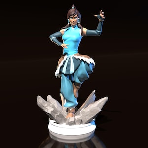 May include: A figurine of a character from the animated series Avatar: The Legend of Korra. The figure is in a dynamic pose, wearing a light blue outfit with dark blue accents and a white fur-trimmed skirt. The figure stands on a base of gray rocks.