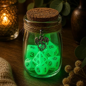 Op de afbeelding: Een glazen pot gevuld met gloeiende groene dobbelstenen, een kurken stopper en een drakenbedel. De pot is omwikkeld met touw en staat op een houten oppervlak. De dobbelstenen zijn genummerd en lichtgevend.