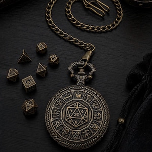 Könnte beinhalten: Ein rundes Taschenuhrgehäuse aus Messing im antiken Stil mit einem zentralen zwanzigseitigen Würfeldesign, umgeben von zwölf eingravierten Symbolen, befestigt an einer passenden Metallkette, begleitet von sieben kleinen polyedrischen Würfeln.