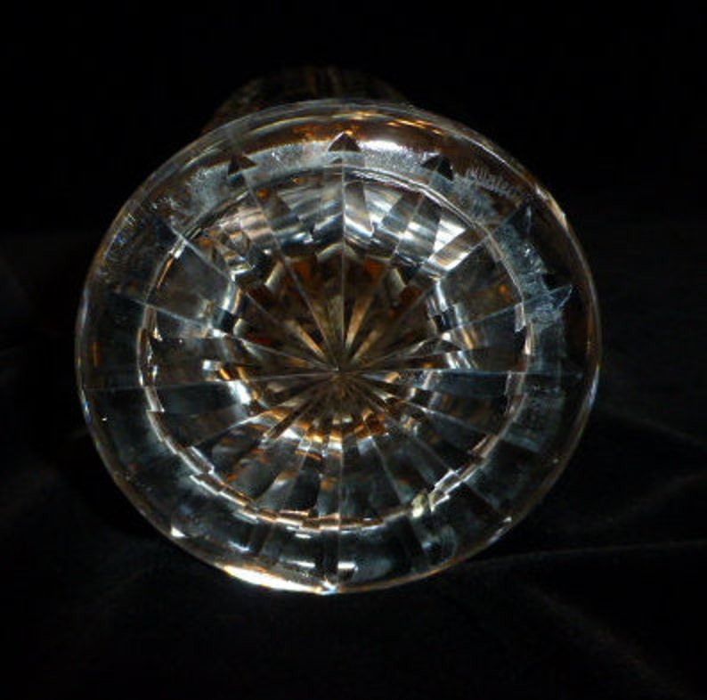 May include: Clear glass vase with a cut crystal design. The vase has a round base and a cylindrical shape.