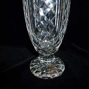 May include: A clear glass vase with a diamond pattern and a wide base. The vase is made of crystal and has a classic design.