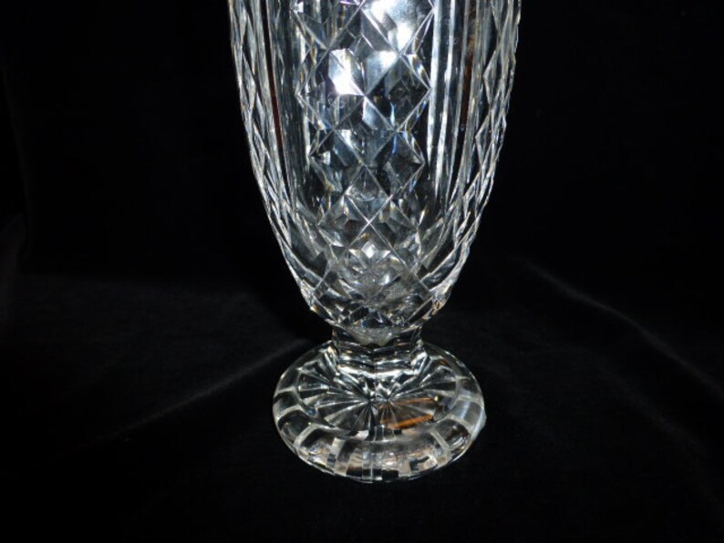 May include: A clear glass vase with a diamond pattern and a wide base. The vase is made of crystal and has a classic design.