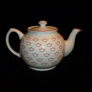 May include: White teapot with a red teapot pattern. The teapot has a lid and a spout.