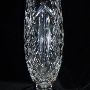 May include: A clear glass vase with a cut crystal design. The vase has a wide base and a narrow neck.