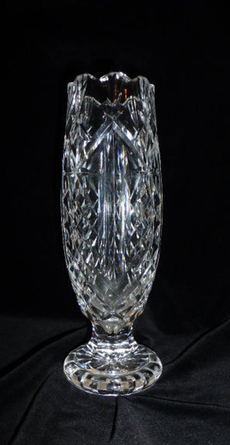 May include: A clear glass vase with a cut crystal design. The vase has a wide base and a narrow neck.