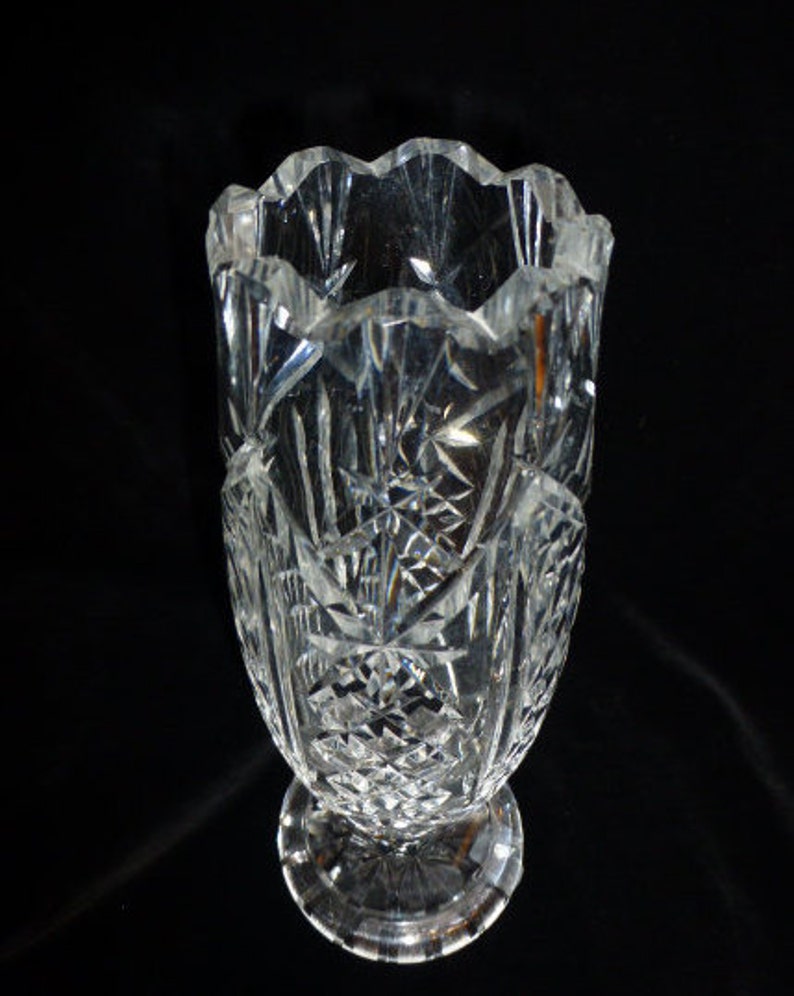 May include: A clear glass vase with a cut crystal design. The vase has a wide mouth and a narrow base.