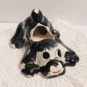 May include: Black and white ceramic dog planter with a hole in the back for planting. The dog has large eyes and a red mouth.