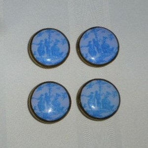 May include: Four blue and white ceramic buttons with a gold rim. Each button features a silhouette of people in a pastoral scene.