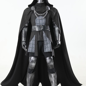 May include: A full-body costume featuring a metallic silver mask, a long black hooded cloak, and a black tunic with a grey patterned panel. The outfit includes silver-toned shoulder armor, a chain link chest piece, gauntlets, and matching leg armor.