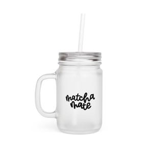 Könnte beinhalten: Ein klares Glas-Einmachglas mit silbernem Deckel und Griff. Auf dem Glas steht in schwarzer Schrift "matcha mate". Ein weißer Strohhalm ist in das Glas gesteckt.