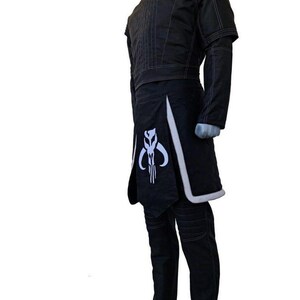 May include: Black costume with a high collar, short sleeves, and a skirt-like panel. The costume features white trim and a white emblem on the front. The pants are black with stitched details. The costume is displayed on a mannequin.