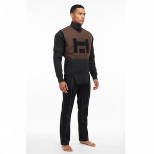 May include: A brown and black vest with a black turtleneck and black pants. The vest has a geometric design in black and white stitching. The pants have white stitching. The outfit is a futuristic design.