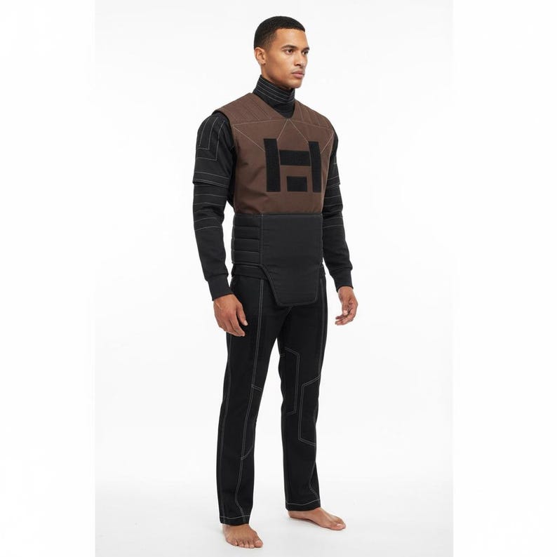 May include: A brown and black vest with a black turtleneck and black pants. The vest has a geometric design in black and white stitching. The pants have white stitching. The outfit is a futuristic design.