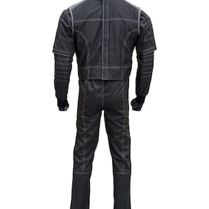 May include: A black racing suit with white stitching details. The suit features a jacket and pants design, with a high collar and long sleeves. The suit is displayed on a mannequin, showcasing the back view of the garment.