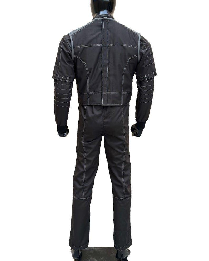 May include: A black racing suit with white stitching details. The suit features a jacket and pants design, with a high collar and long sleeves. The suit is displayed on a mannequin, showcasing the back view of the garment.