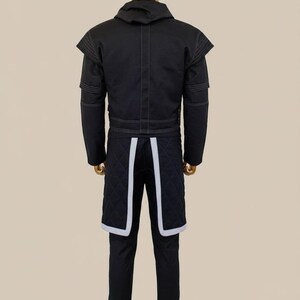 May include: Black jacket and pants set with white stitching and accents. The jacket has a hood and structured shoulders. The pants feature quilted panels with white trim. The outfit is displayed on a mannequin.