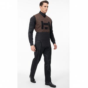 May include: A person wearing a brown vest with a large black "H" design, a black long-sleeved shirt, black pants with white stitching, and black shoes. The vest has a geometric pattern and the pants have a unique design.