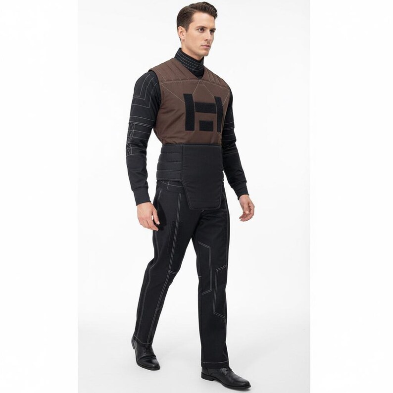 May include: A person wearing a brown vest with a large black "H" design, a black long-sleeved shirt, black pants with white stitching, and black shoes. The vest has a geometric pattern and the pants have a unique design.