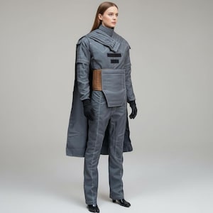 May include: A gray futuristic-style outfit with a high collar, cape, and pants. The outfit features white stitching, a brown belt, and black gloves. The model is wearing black shoes. The overall design suggests a sci-fi or cosplay theme.