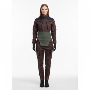 Peut inclure: Combinaison marron avec des d&eacute;tails noirs et une ceinture verte. La tenue a un col montant et des manches longues. Le mod&egrave;le porte des gants et des bottes noirs. La combinaison a un design futuriste.