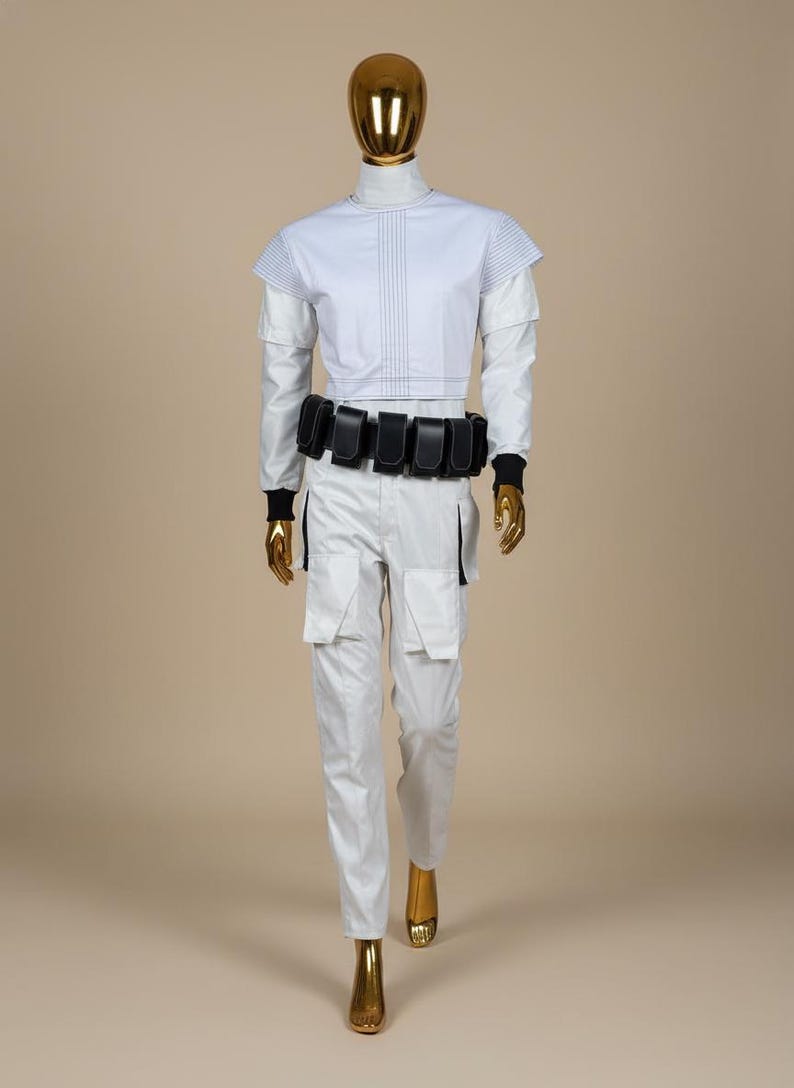 May include: A futuristic white outfit on a mannequin. The ensemble includes a high-collared top with blue stitching, matching trousers with cargo pockets, and a black belt with pouches. The mannequin has a gold head and hands.