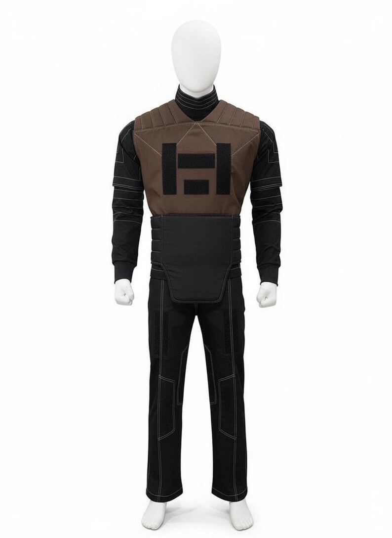 May include: A full black tactical uniform on a mannequin. The uniform includes a brown vest with a black emblem, a black long-sleeve shirt, black pants with white stitching, and a black belt.