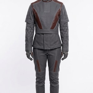 May include: A gray jumpsuit with brown accents, featuring a high collar and quilted sleeves. The outfit includes matching gloves and pants with brown details. The overall design suggests a futuristic or tactical theme.