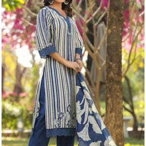 May include: A long-sleeved tunic featuring vertical blue and cream stripes with a floral pattern at the hem, paired with solid blue trousers and a matching blue and cream floral print scarf. The tunic includes blue lace trim at the neckline and cuffs.
