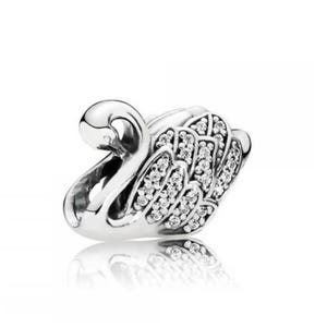 May include: A silver swan charm with a curved neck and detailed wings. The wings are embellished with small, clear gemstones. The charm is reflective and sits on a white background, suggesting a jewelry or accessory item.