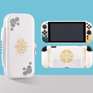 May include: White Nintendo Switch console and case with gold and black decorative designs. The console has a black screen and black buttons. The case has a zipper and a handle. The designs include geometric shapes and a central emblem.