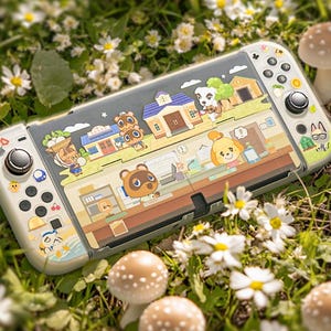 May include: A white Nintendo Switch console with a custom Animal Crossing design. The design features various characters and scenes from the game, including Tom Nook, Isabelle, and the player's house. The console is surrounded by white flowers and mushrooms.