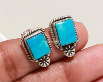 Op de afbeelding: Een paar rechthoekige oorknopjes met helderblauwe turkooisstenen gezet in zilver. Elke oorbel heeft een gedraaide touwrand en een klein zilveren bloemdetail aan de basis. De tekst "silverartisianusa" is zichtbaar op de stenen.